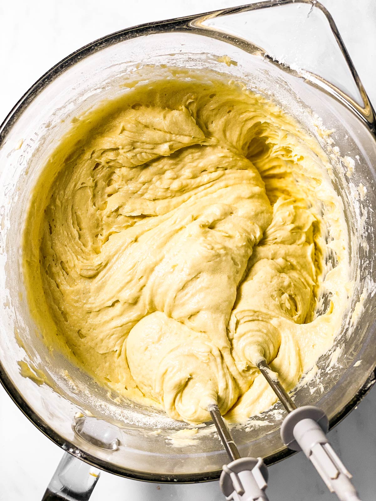 lemon cake batter in glass bowl with mixer beaters