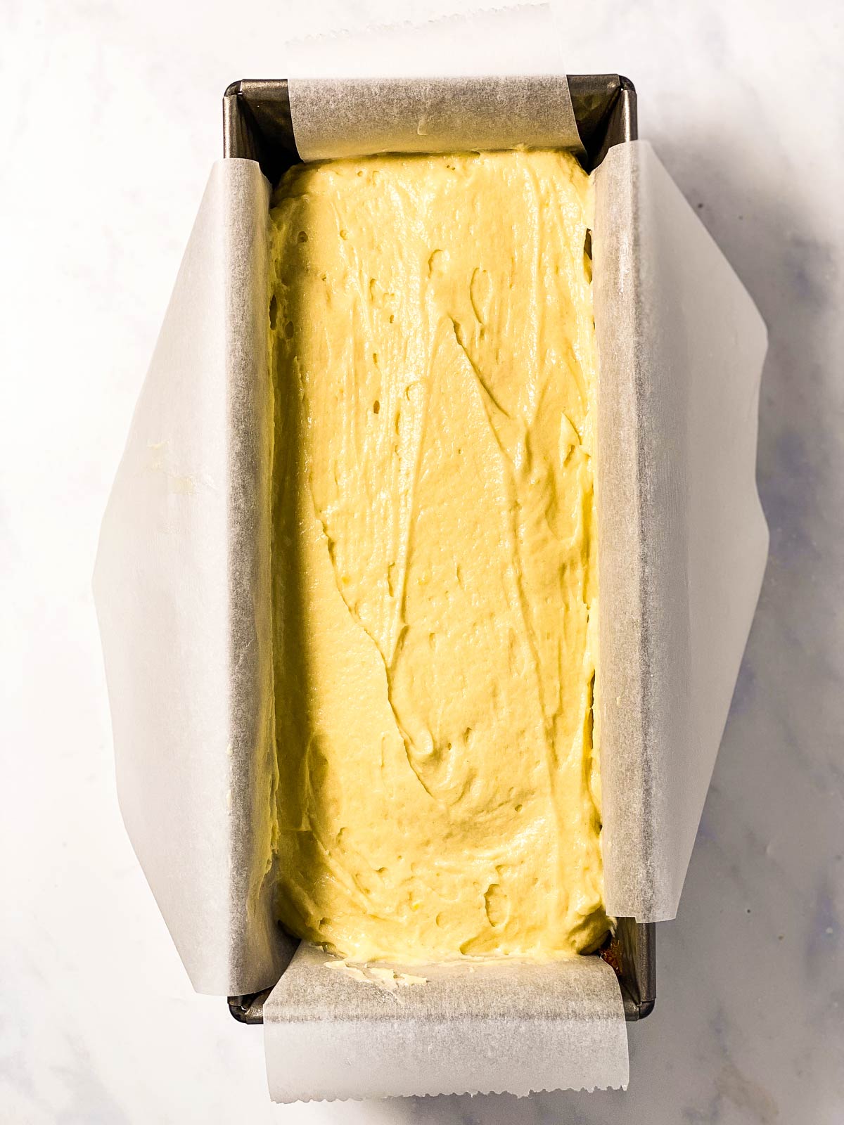 lemon cake batter in lined loaf pan