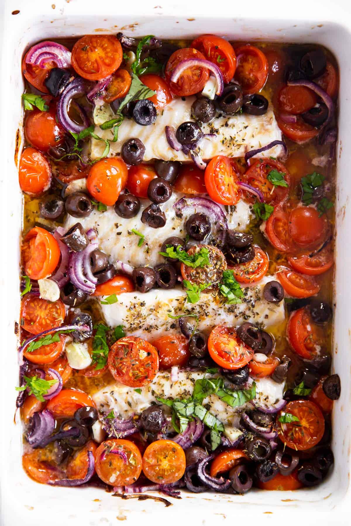 close up photo of white casserole dish with mediterranean baked cod inside