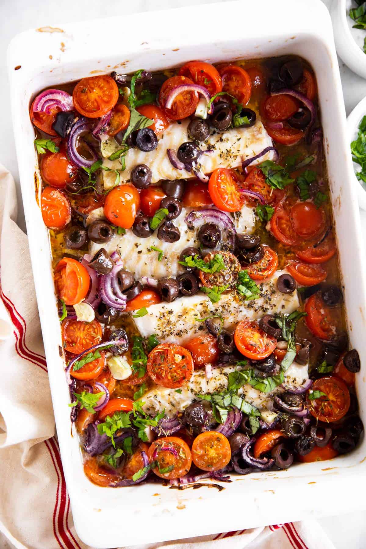 overhead view of white casserole dish filled with mediterranean baked cod