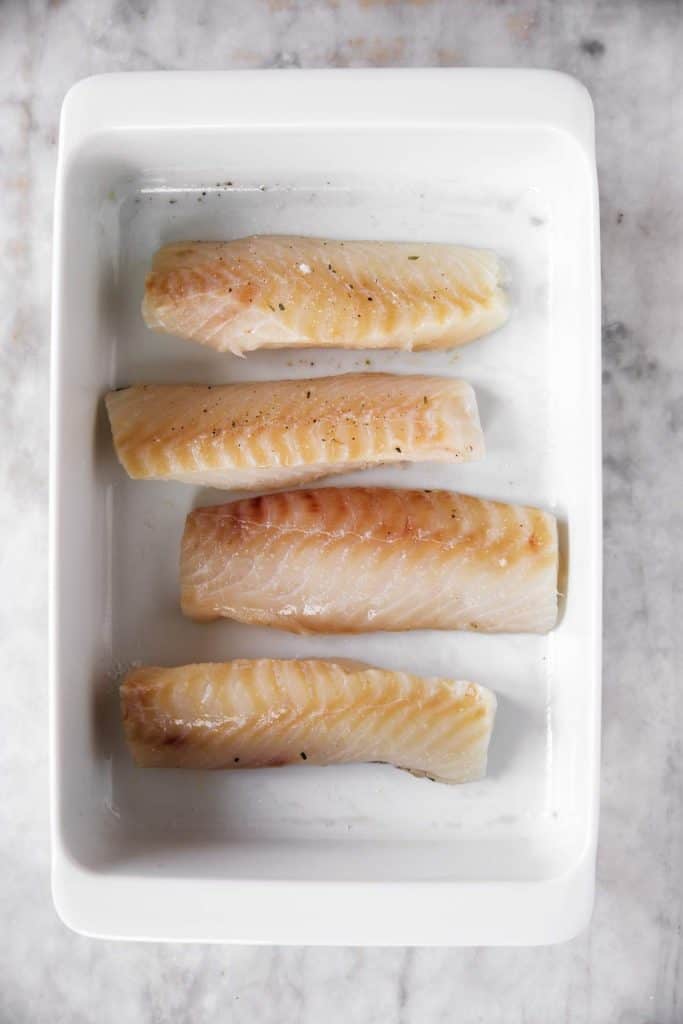 four cod fillets in white casserole dish