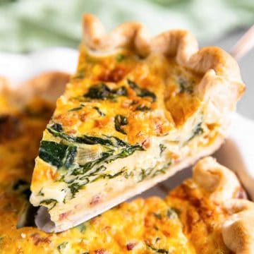 lifting a slice of spinach bacon quiche from the pie dish