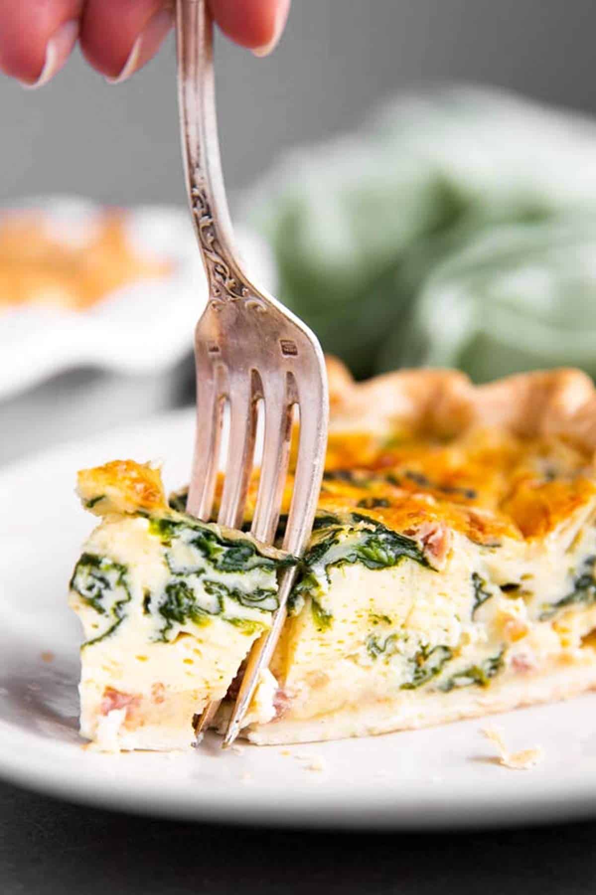 fork in slice of spinach bacon quiche