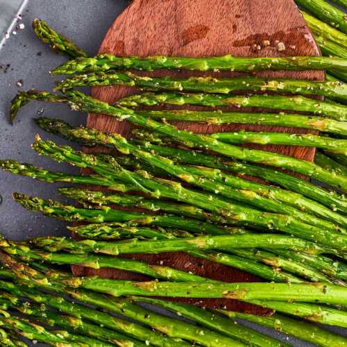 Scooping roasted asparagus with a wooden spatula.