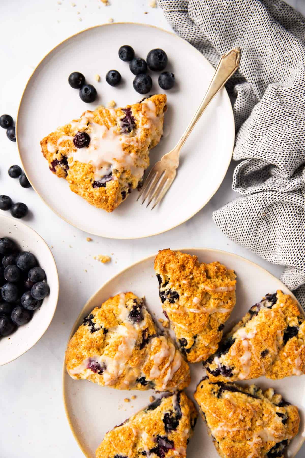 top down view on two plates with blueberry scones on a light surface