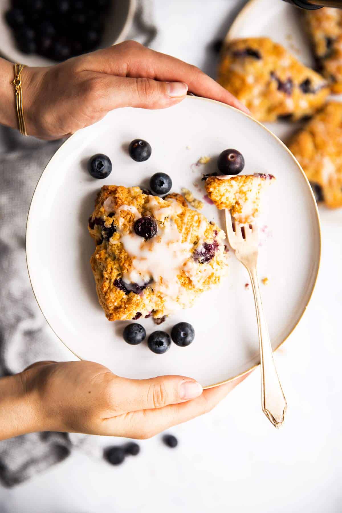 female hands holding plate with blueberry scone