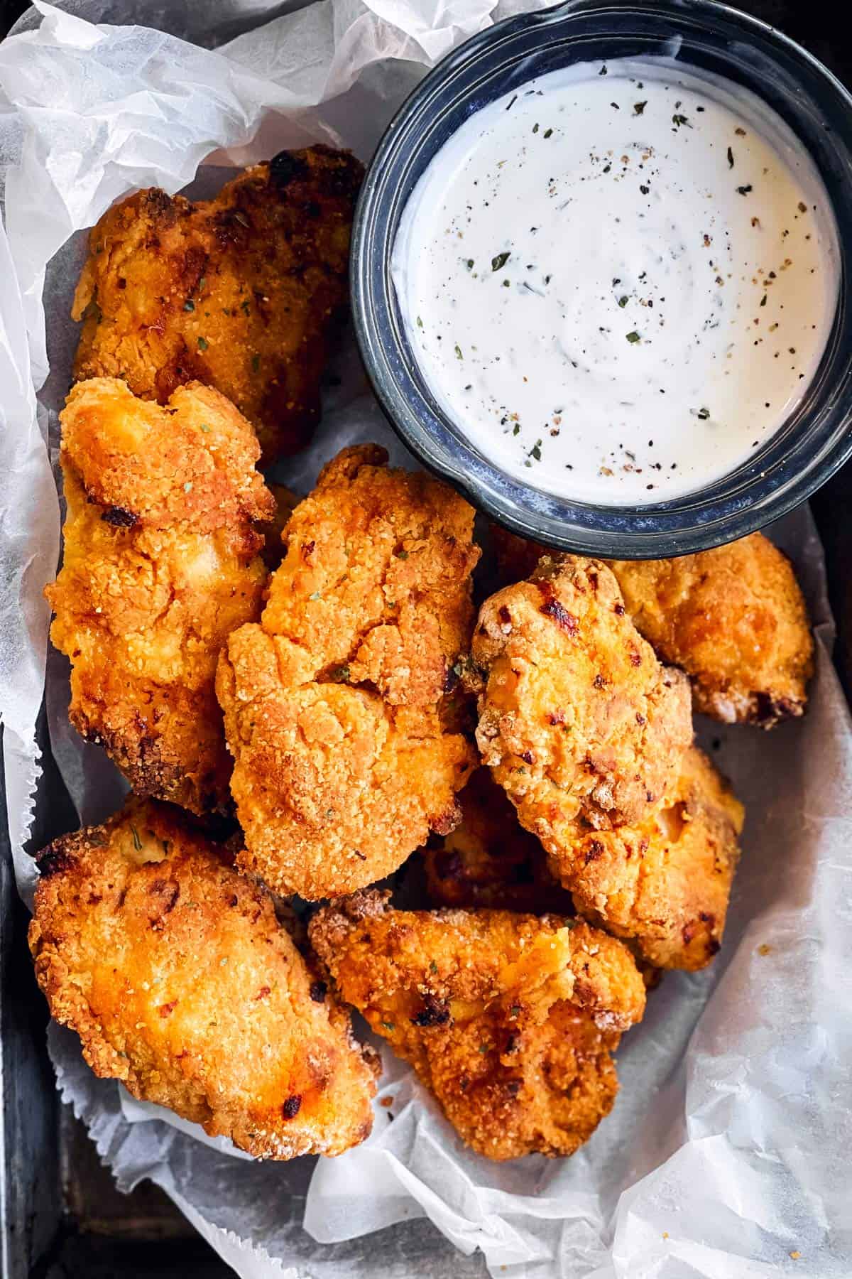 close up photo of buttermilk oven fried chicken on a lined pan