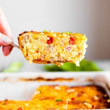 female hand lifting slice of hash brown breakfast casserole out of casserole dish