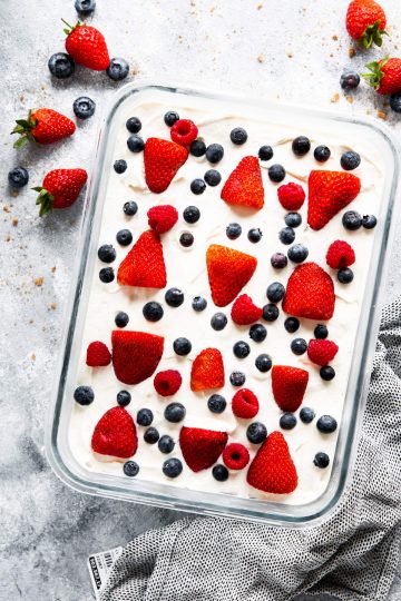 A table of Memorial Day desserts featuring a flag cake, red, white, and blue fruit parfaits, and star-shaped cookies.