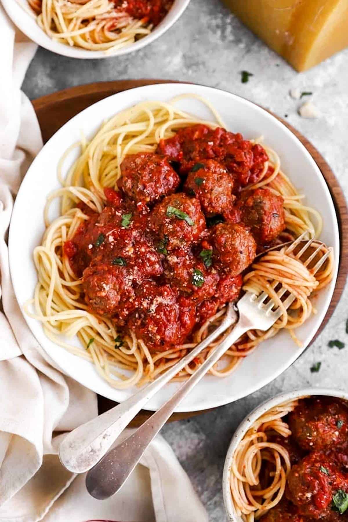 spaghetti and Italian meatballs on plate and in bowls