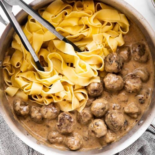skillet with Swedish meatballs and noodles on light surface