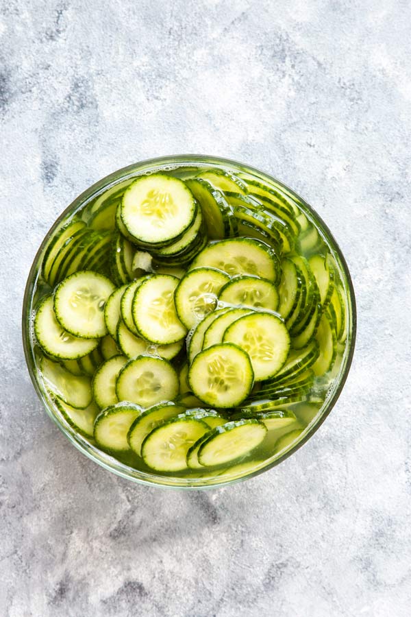 cucumber slices soaking in salt water in a glass bowl