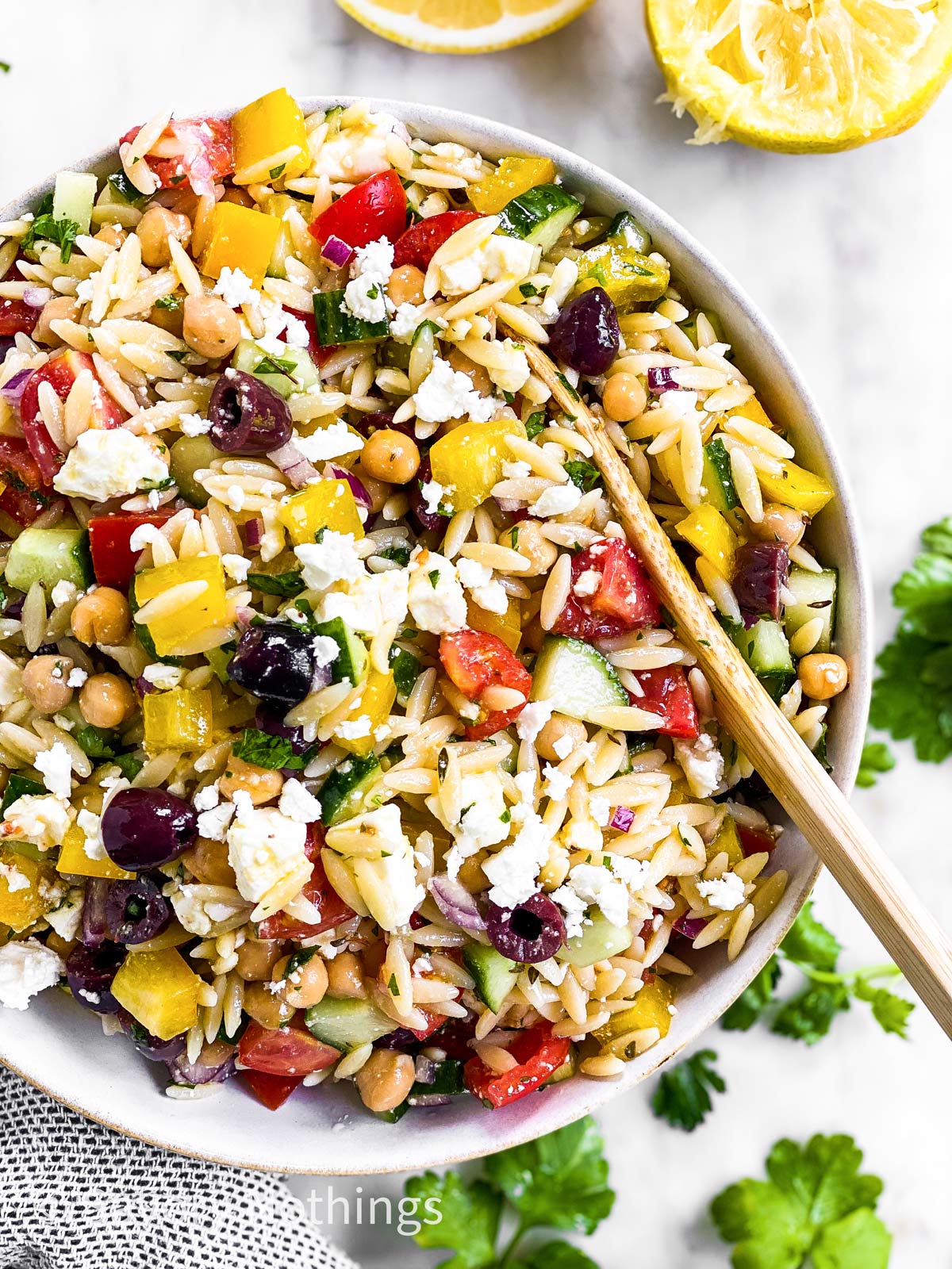 overhead close up view of Greek orzo salad in white bowl