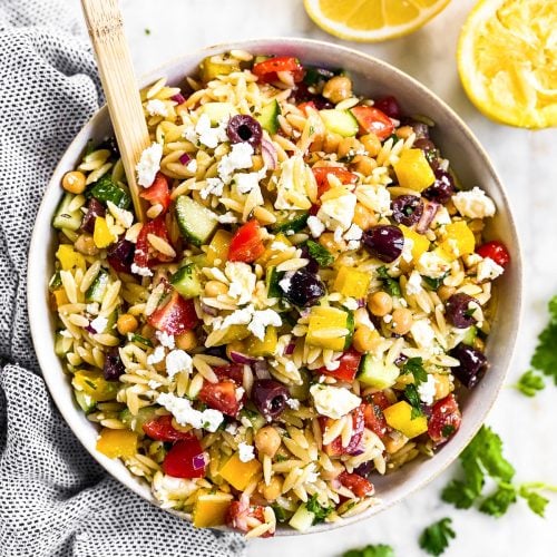 overhead view of greek orzo salad in white bowl