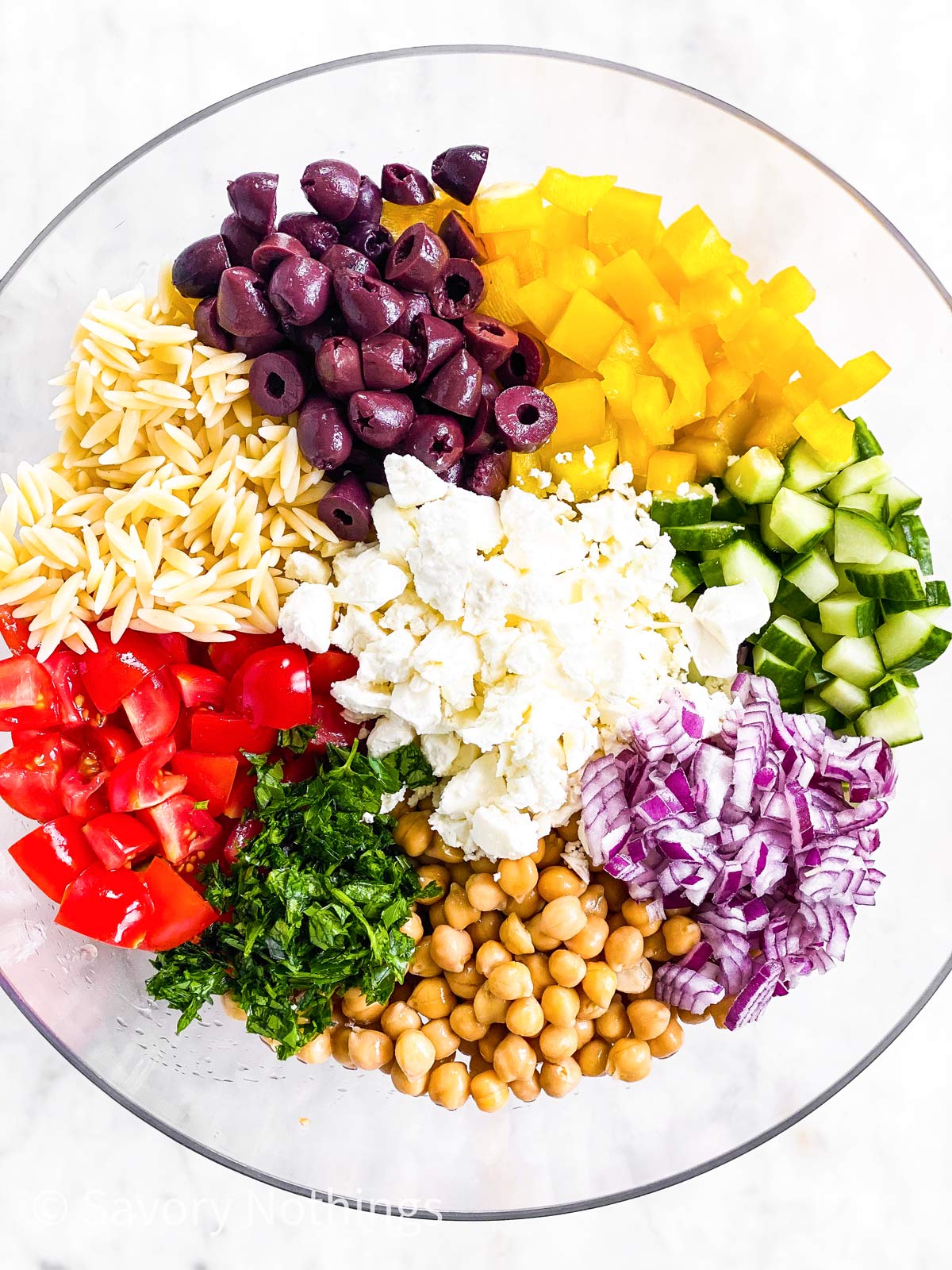 ingredients for Greek orzo salad in glass bowl