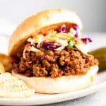 sloppy joes with coleslaw on a white plate
