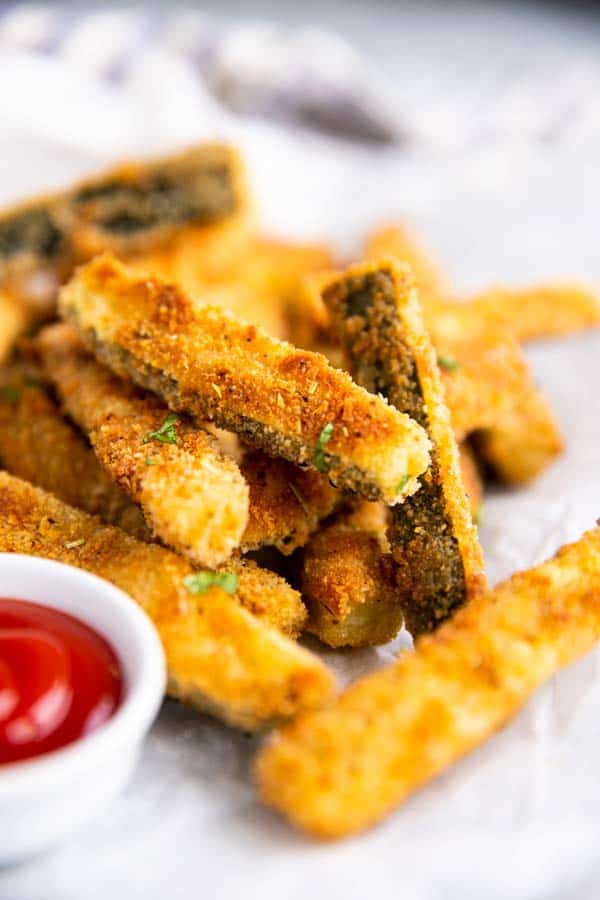 pile of parmesan zucchini fries on a sheet of baking parchment