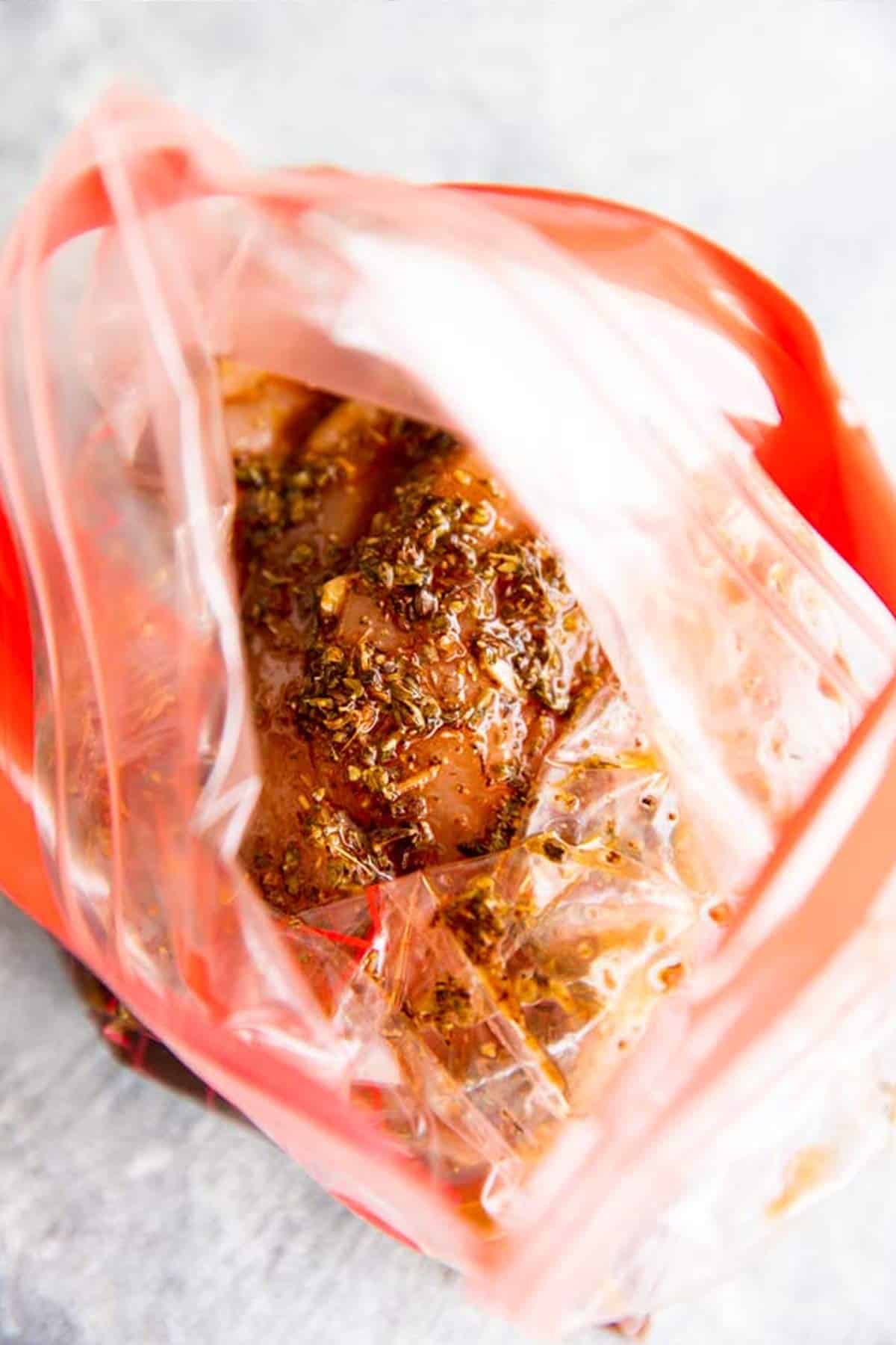 raw chicken breast in a ziptop bag with balsamic chicken marinade