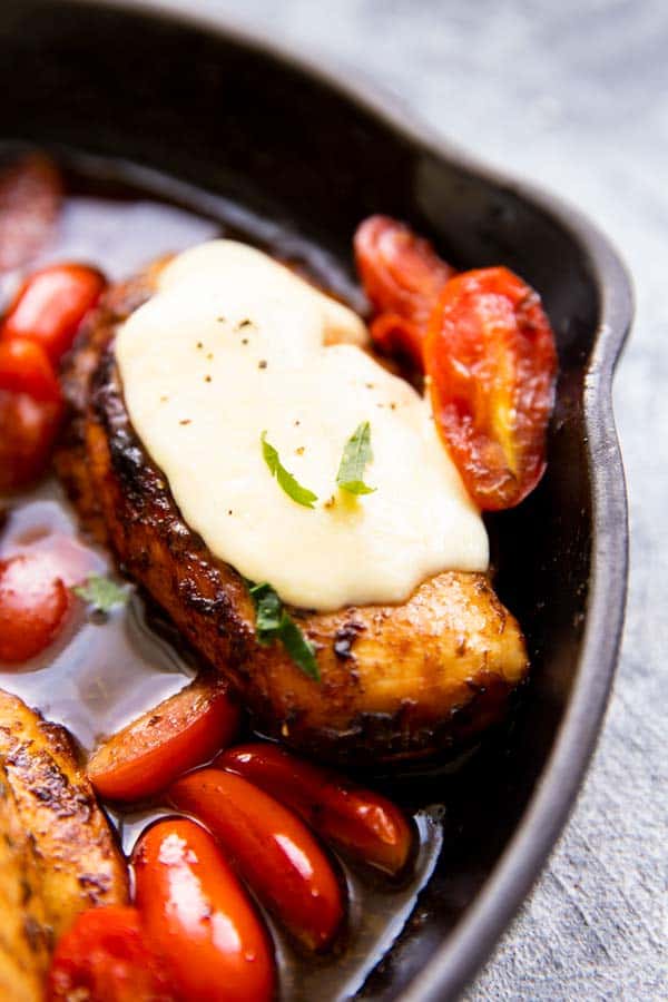 close up photo of a chicken breast in balsamic glaze with tomatoes and mozzarella cheese