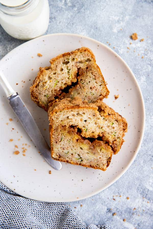 two slices of cinnamon swirl zucchini bread on a white plate with a knife