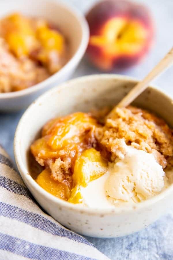 close up photo of a bowl with peach cobbler and ice cream