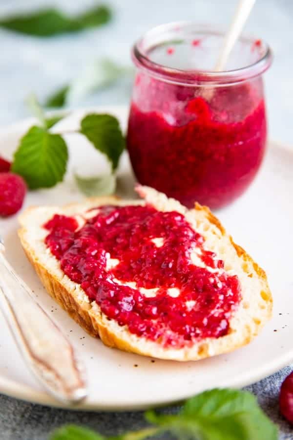 slice of no knead bread with homemade raspberry jam on a plate