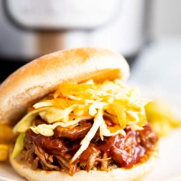 pulled pork sandwich in front of an instant pot pressure cooker