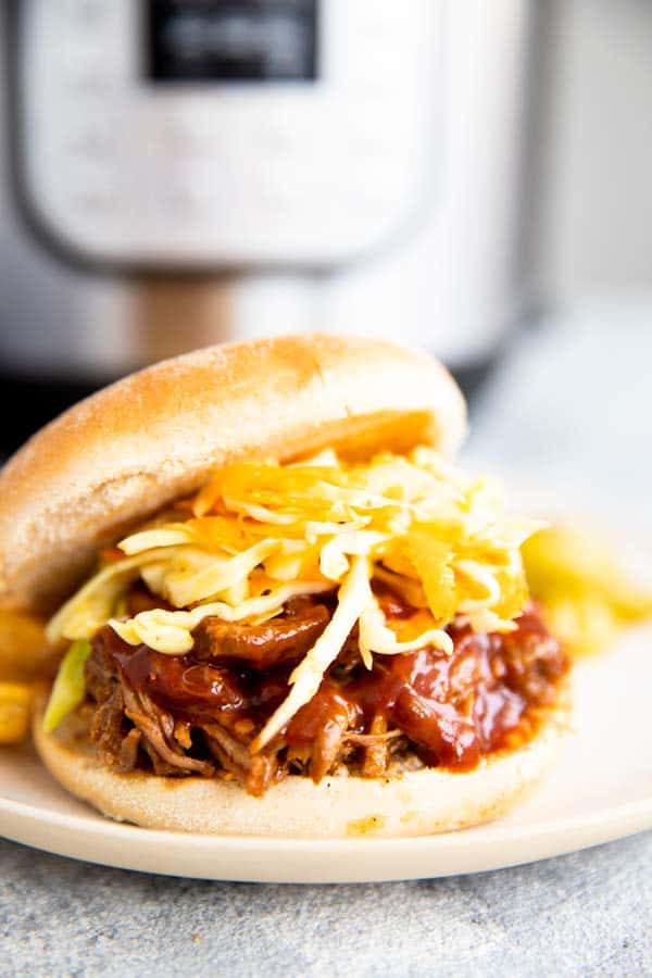 pulled pork sandwich in front of an instant pot pressure cooker