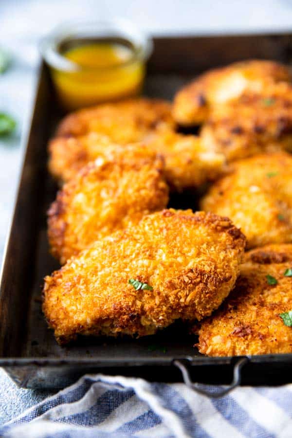 oven fried coconut chicken on a dark pan