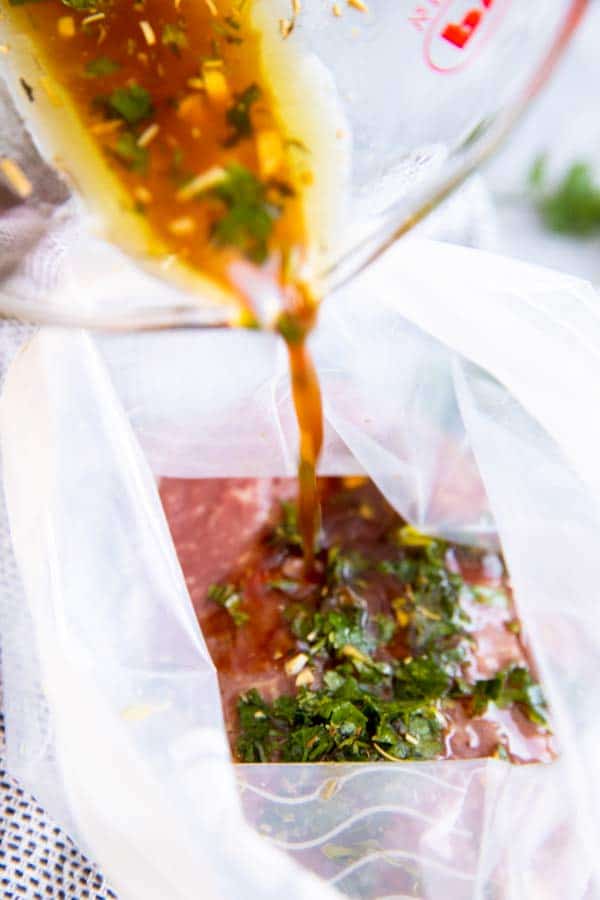 pouring steak marinade over steaks in a plastic bag