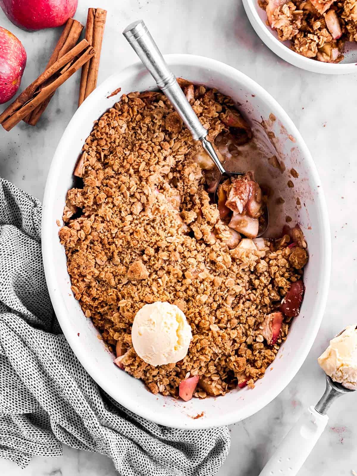 overhead view of apple crisp with ice cream in white baking dish