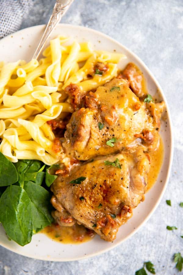 plate with instant pot chicken thighs, pasta and baby spinach