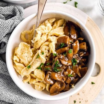 overhead view of white bowl with homemade spaetzle and mushroom gravy