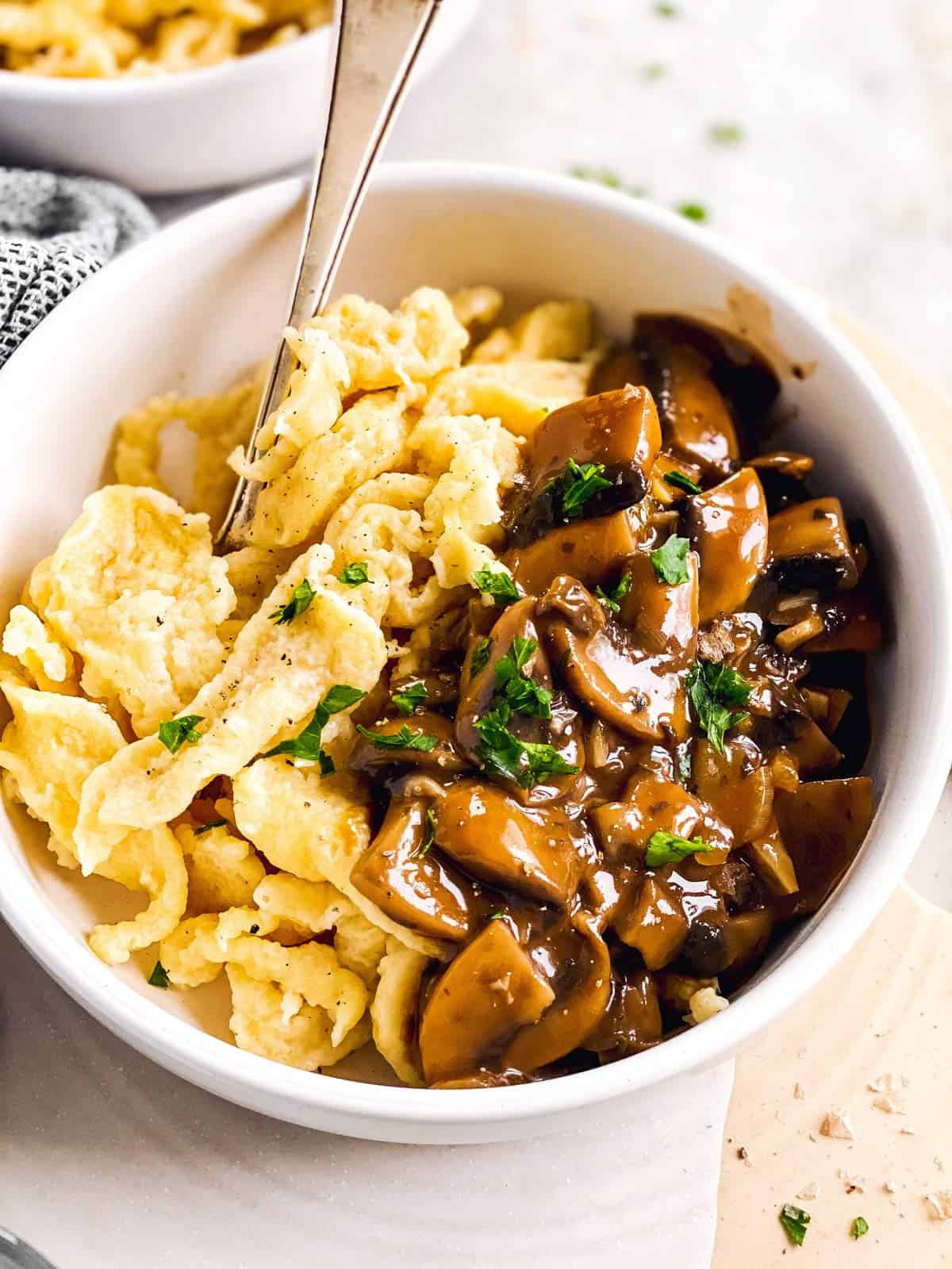 close up photo of spaetzle with mushroom gravy in a white bowl