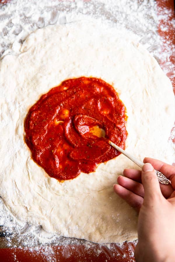 spreading pizza sauce on pizza dough