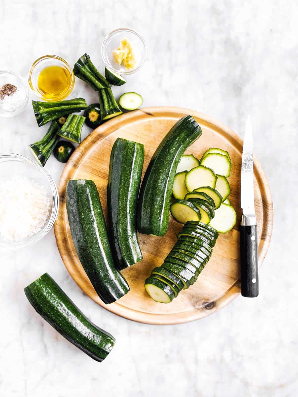 wooden board with partly sliced zucchini and a knife