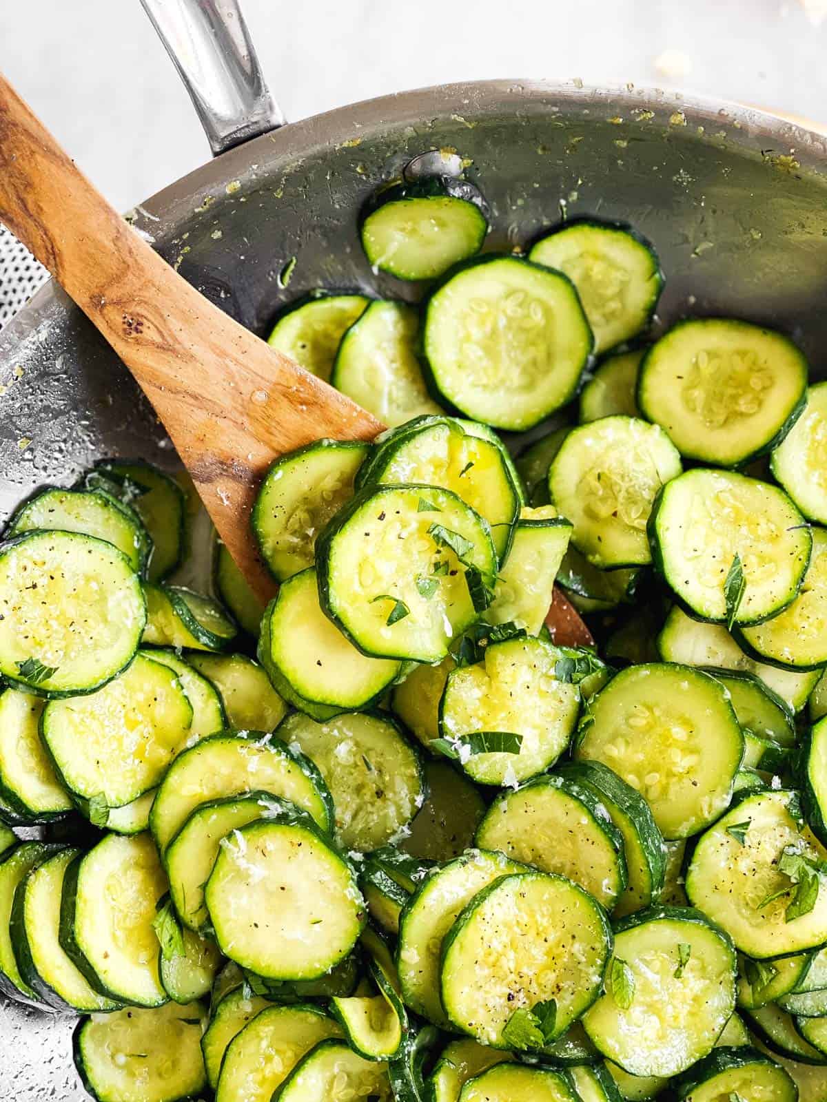 overhead view of wooden spoon in pan with sautéed zucchini slices