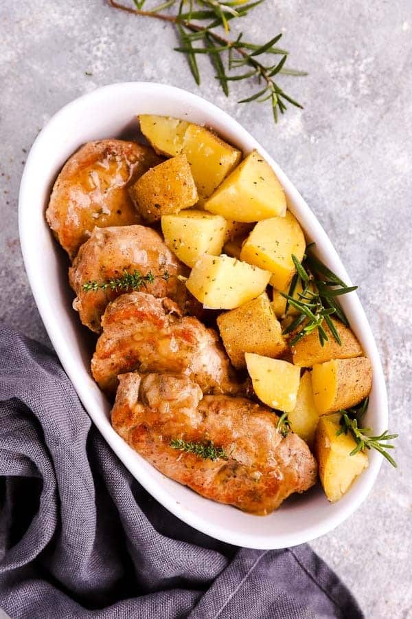 white dish filled with pork chops and rosemary potatoes
