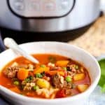 bowl of beef barley soup in front of an electric pressure cooker