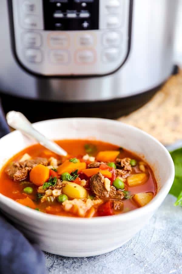 bowl of beef barley soup in front of an electric pressure cooker