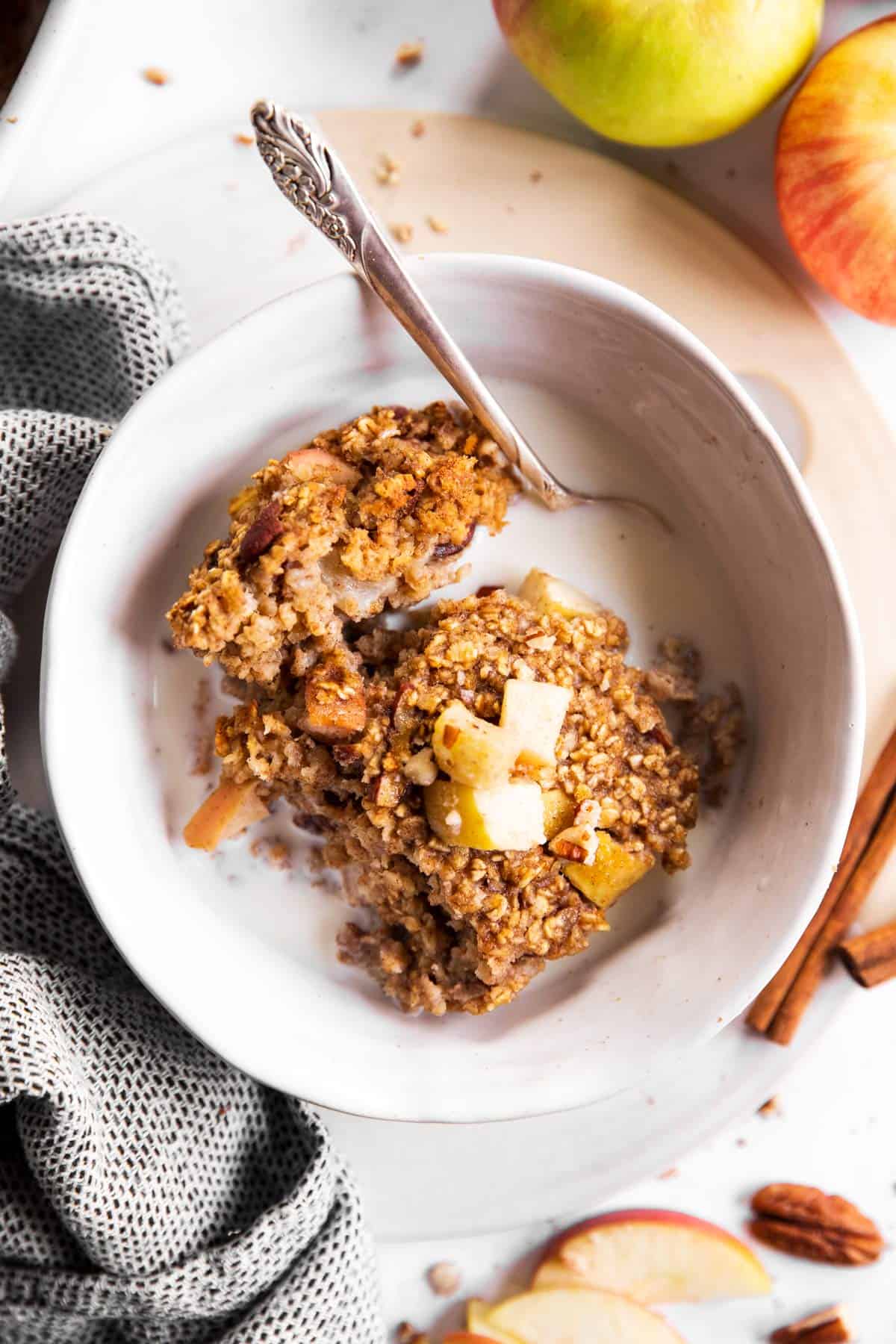 overhead view of white bowl with apple baked oatmeal and milk