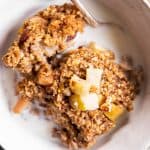 close up overhead view of white bowl with apple baked oatmeal and milk