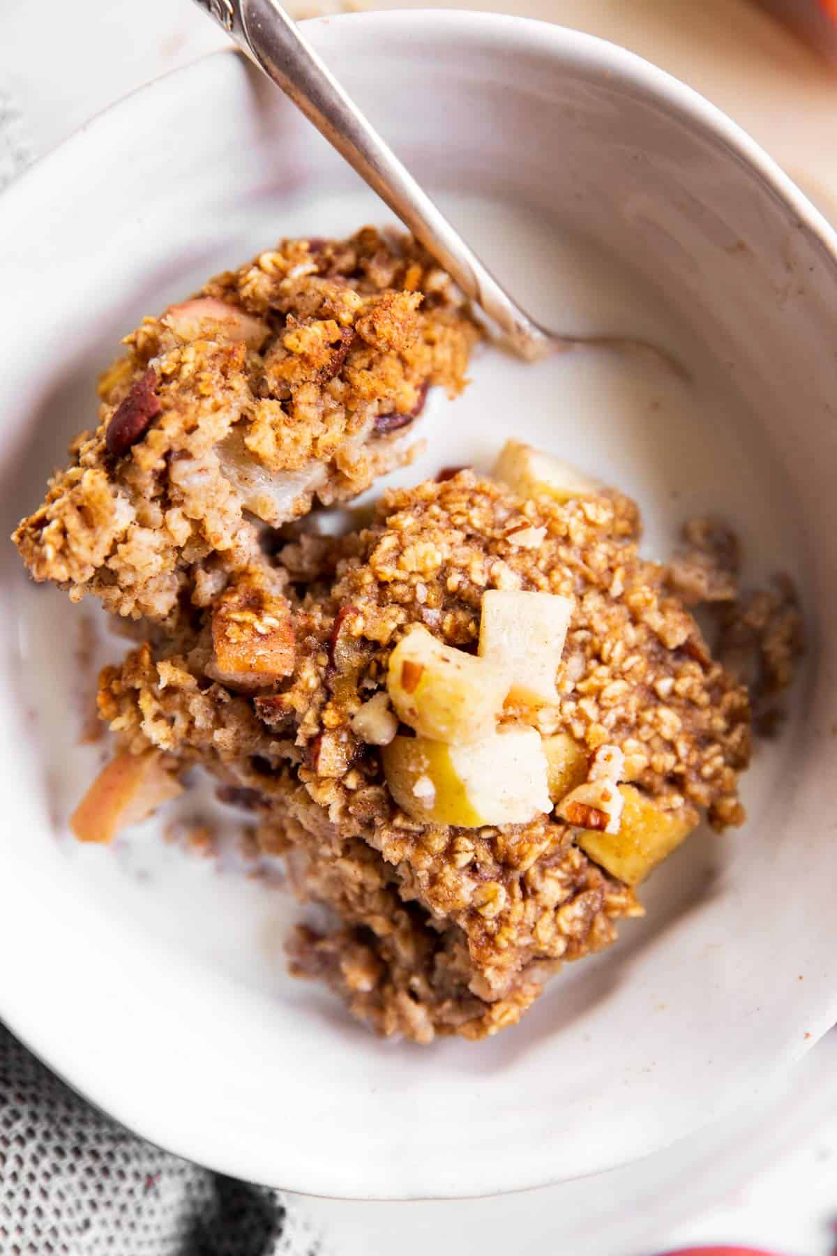 close up overhead view of white bowl with apple baked oatmeal and milk