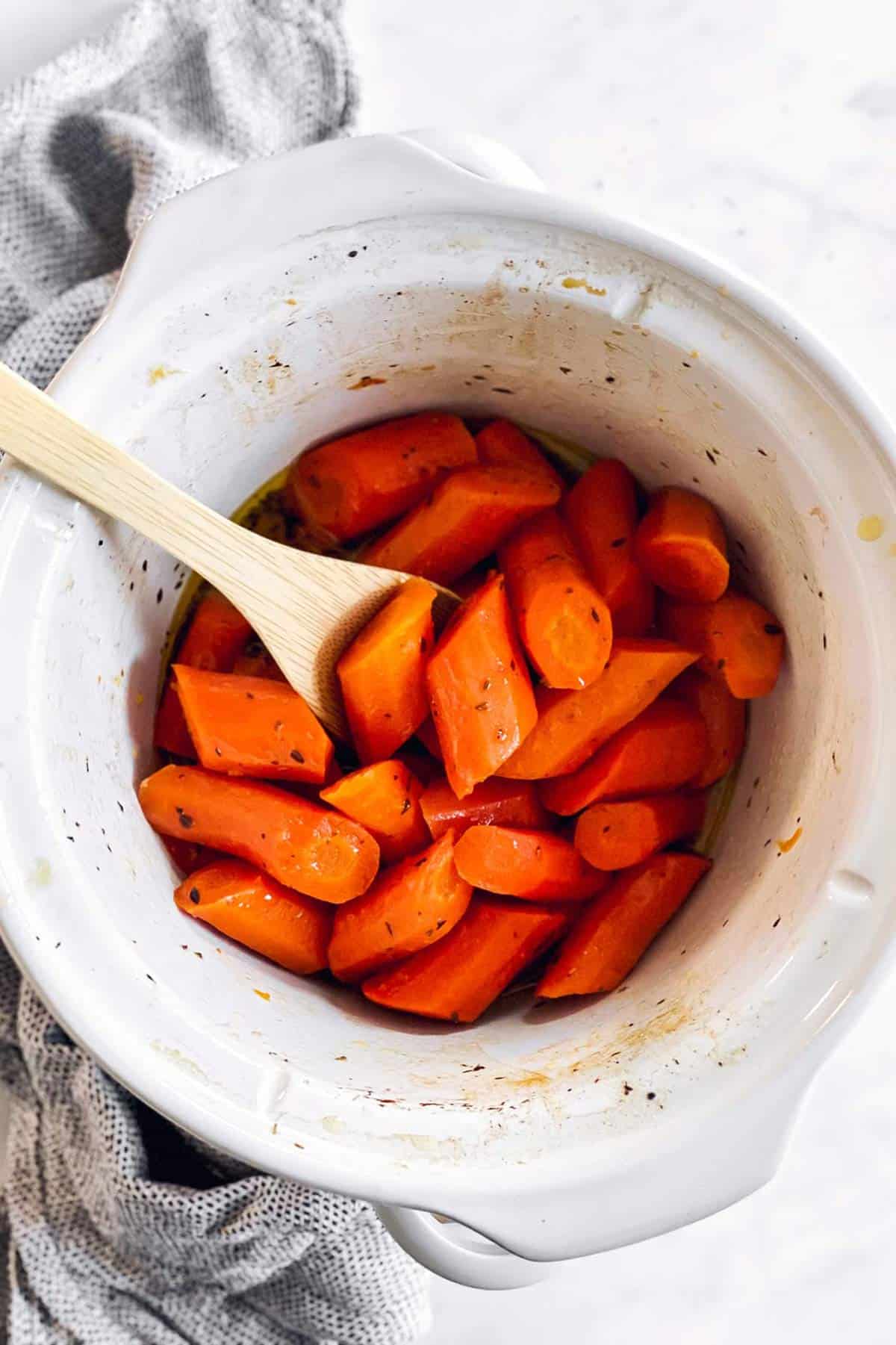 overhead view of white crockpot with glazed carrots