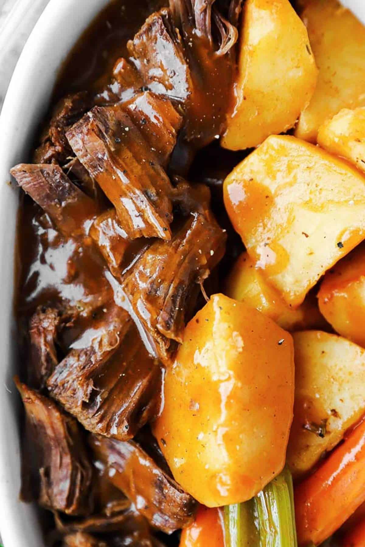 close up photo of beef roast with gravy in dish with vegetables