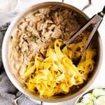 view down on a pan with stroganoff and egg noodles, kitchen tongs sticking in the noodles