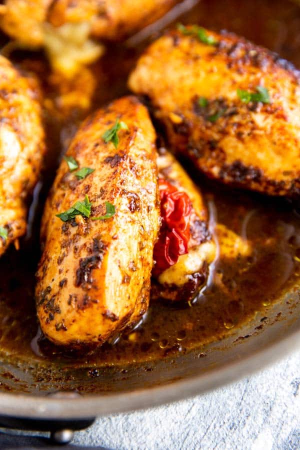 close up photo of a stuffed chicken breast in a pan with balsamic sauce