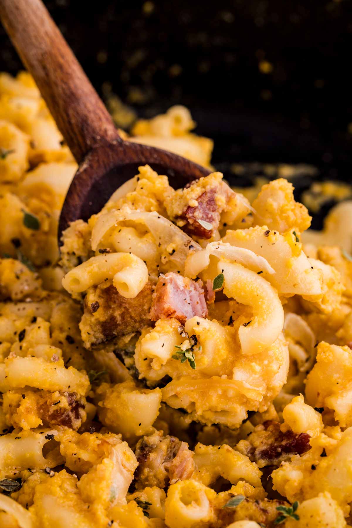 scooping butternut squash Mac and cheese with a wooden spoon