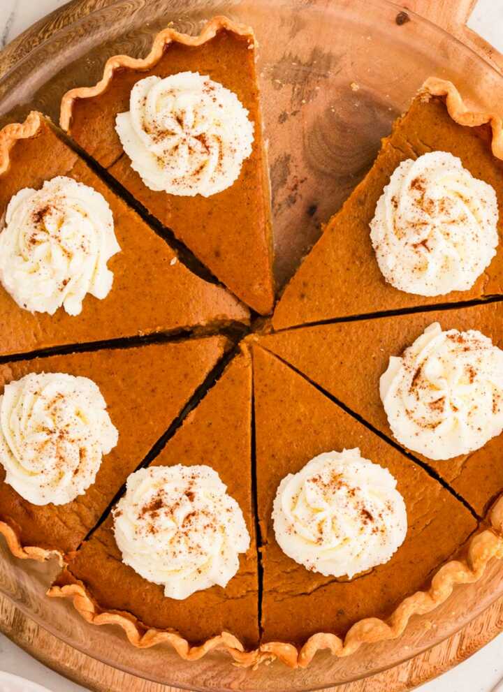 overhead view of sliced pumpkin pie decorated with whipped cream