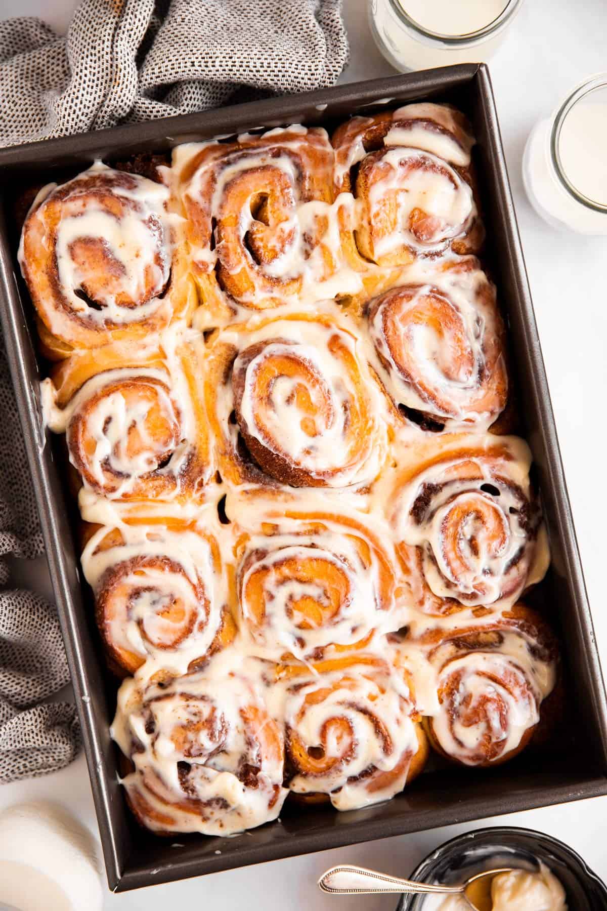 black pan with frosted cinnamon rolls inside